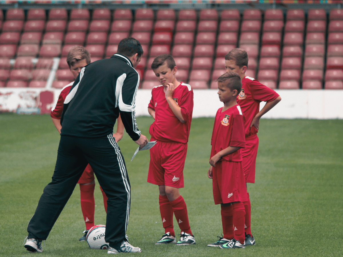 Grassroots-football-coach-with-young-players-football4football